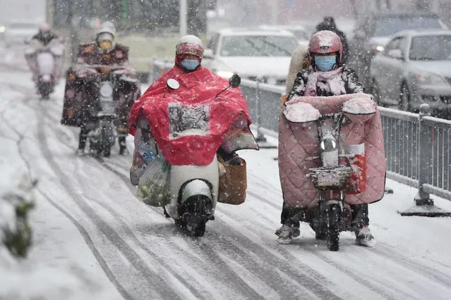 People ride their scooters during heavy snowfall in Huai'an, in eastern China's Jiangsu province on February 4, 2024. (Photo by AFP Photo/China Stringer Network)