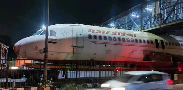 A scrapped Air India aircraft is seen stuck under a pedestrian overbridge in New Delhi, India, Sunday, October 3, 2021. The plane was reportedly being transported by its new owner who purchased it from the airline. (Photo by Kshitiz Kakkar via AP Photo)