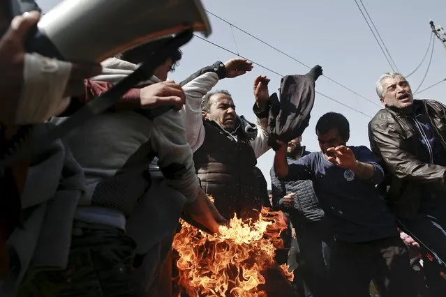 A refugee (C) sets himself on fire as others try to put the fire out during a protest by refugees and migrants demanding that the Greek-Macedonian border be opened, at a makeshift camp near the village of Idomeni, Greece, March 22, 2016. (Photo by Kostas Tsironis/Reuters)