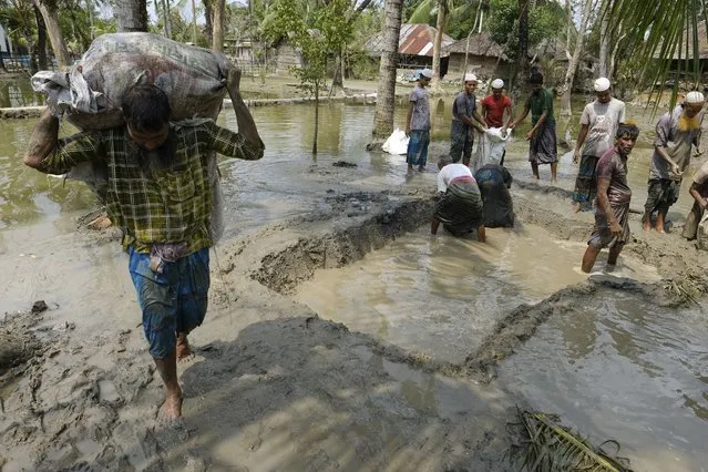 Villagers make a dam with mud in plastic bags to protect their only road in Pratap Nagar, that lies in the Shyamnagar region, in Satkhira, Bangladesh on October 5, 2021. In 1973,  0.833 million hectares were affected by the encroaching seawater, accelerated by more frequent cyclones and higher tides, that has contaminated water supplies. That's bigger than the U.S. state of Delaware. That increased to 1.02 million hectares in 2000, and to 1.056 million hectares in 2009, according to Bangladesh’s Soil Resources Development Institute. (Photo by Mahmud Hossain Opu/AP Photo)