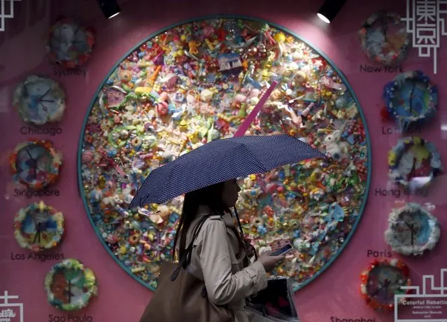 A pedestrian holding an umbrella walks past a display window at a shopping district in Tokyo, Japan, March 7, 2016. (Photo by Yuya Shino/Reuters)