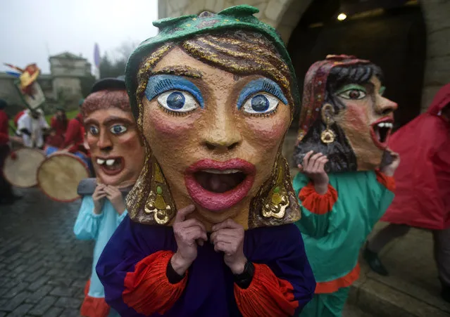 Mask-wearing revelers make their way to the Carnival parade in Barcelos, northern Portugal, Sunday, March 2, 2014. Giant puppets and big heads, “Cabecudos” and “Gigantones” in Portuguese, are basic ingredients of northern pilgrimages, made with a wire frame and wood, coated paper and cloth, covered with plaster and glue and paint. (Photo by Paulo Duarte/AP Photo)