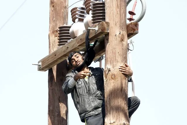 A Pakistani migrant threatens to hang himself from a utility pole during a demonstration inside the Moria registration centre on the Greek island of Lesbos, April 6, 2016. (Photo by Giorgos Moutafis/Reuters)
