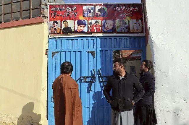 From left to right, Ajmal Ahmadi, Emal Ahamdi, and Romal Ahmadi, three brothers of Zemerai Ahmadi who was one of ten family members who was killed in an errant U.S. drone strike in August, stand in front of a banner that reads in Dari, “Martyrs of Ahmadi family”, over the gate of the Ahmadi family home, in Kabul, Afghanistan, Tuesday, December 14, 2021. The Afghan survivors of the U.S. drone strike said Tuesday they are frustrated and saddened by a decision that no U.S. troops involved in the strike would face disciplinary action. (Photo by Khwaja Tawfiq Sediqi/AP Photo)