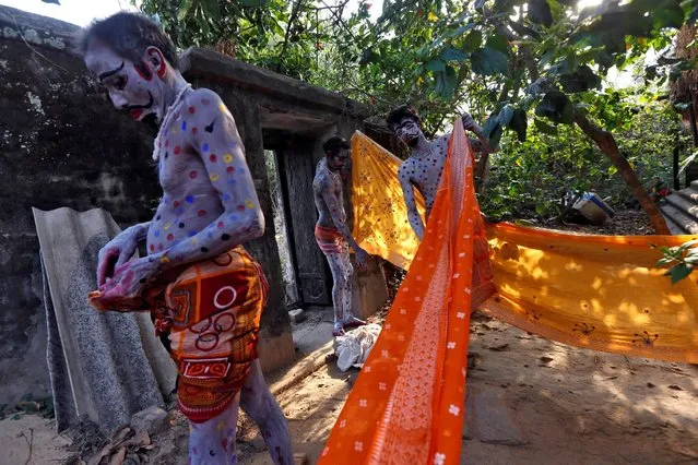 Devotees with their bodies painted prepare to wear saree, a traditional Indian cloth used for women's clothing, before taking part in a ritual as part of the annual Shiva Gajan religious festival at Sona Palasi village, in West Bengal, India, April 11, 2016. (Photo by Rupak De Chowdhuri/Reuters)
