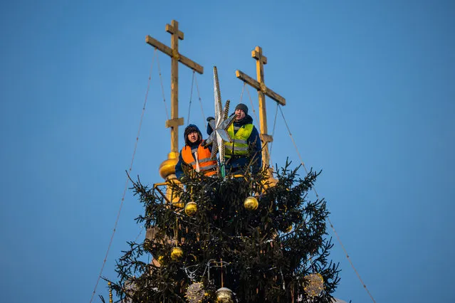 Workers decorate the main Russian 28-metre-high New Year tree at the Kremlin's Sobornaya Square in downtown Moscow on December 22, 2021, with the air temperature at around minus 21 degrees Celsius. (Photo by Dimitar Dilkoff/AFP Photo)