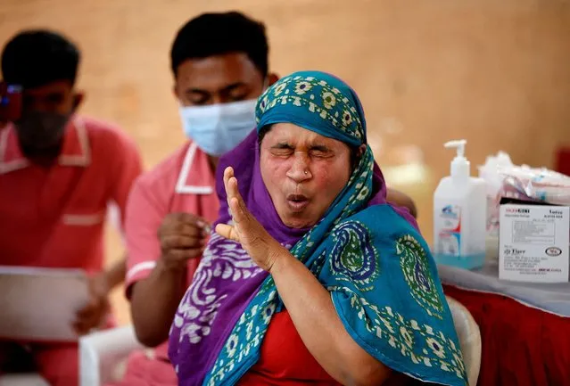 A woman reacts as she receives a dose of the COVISHIELD vaccine against the coronavirus disease (COVID-19), manufactured by Serum Institute of India, at a vaccination centre in Ahmedabad, India, December 27, 2021. (Photo by Amit Dave/Reuters)