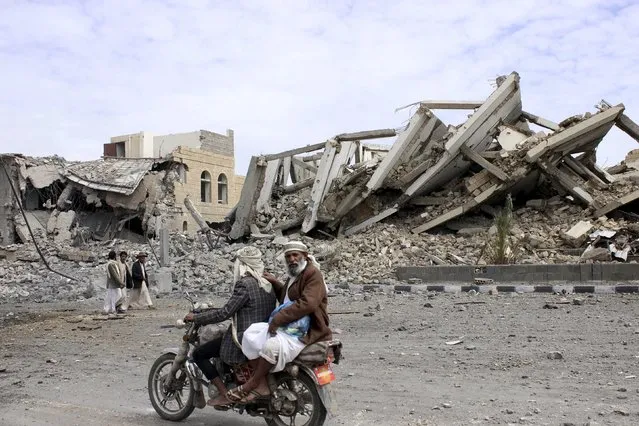 People ride on a motorcycle as they pass by a police headquarters destroyed by a Saudi-led air strike in Yemen's northwestern city of Saada May 7, 2015. (Photo by Reuters/Stringer)