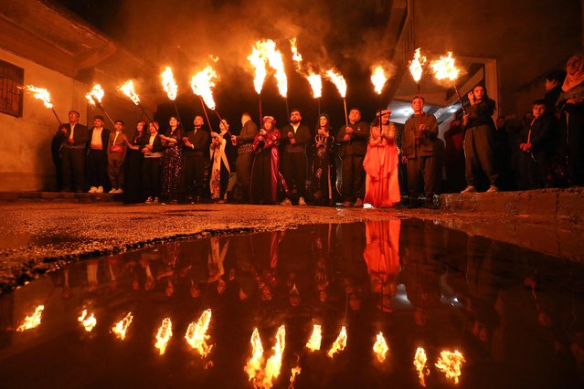 Syrian Kurds march with torches during the celebration of Nowruz, the Persian New Year, in the Kurdish-majority city of Qamishli in Syria's northeastern Hasakeh province, on March 20, 2024. The Persian New Year is an ancient Zoroastrian tradition celebrated by Iranians and Kurds which coincides with the vernal (spring) equinox and is calculated by the solar calendar. (Photo by Delil souleiman/AFP Photo)