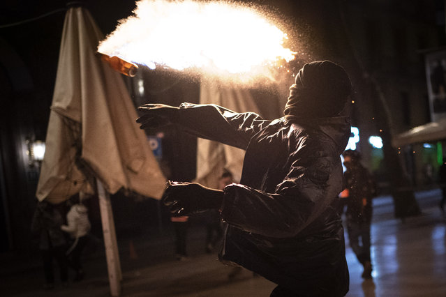 A protestor throws a molotov cocktail at police during clashes following a protest condemning the arrest of rap singer PPablo Hasél in Barcelona, Spain, Saturday, February 27, 2021. After a few days of calm, protests have again turned violent in Barcelona as supporters for a jailed Spanish rapper went back to the streets. (Photo by Emilio Morenatti/AP Photo)