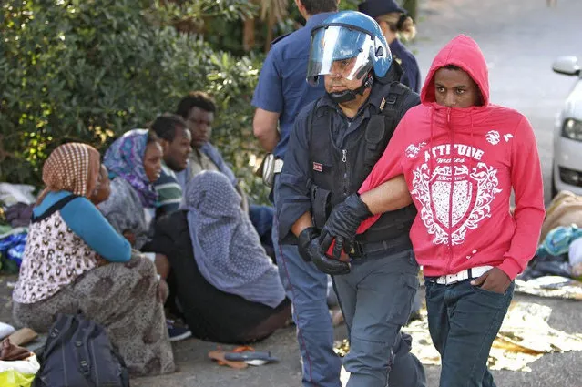 A migrant is evacuated by Italian police at the Franco-Italian border near Menton, southeastern France, Tuesday, June 16, 2015. Some 150 migrants, principally from Eritrea and Sudan, have been trying since last Friday to cross the border from Italy but have been blocked by French and Italian police. (AP Photo/Lionel Cironneau)