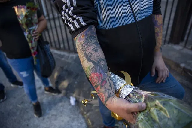 Fernando Contretas, whose arms is tattooed with an image of Jesus Christ wearing a crown of thorns, stands in line outside La Merced Catholic church, waiting to place flowers in front of a statue of Jesus Christ, during Holy Week in Guatemala City, Tuesday, March 30, 2021. The traditional Jesus of Nazareth procession known as “La Resena” was cancelled for a second consecutive year as a measure to contain the spread of the coronavirus. (Photo by Moises Castillo/AP Photo)