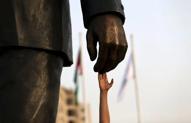 A Palestinian man touches the Mandela statue during the inauguration of Nelson Mandela Square in the West Bank city of Ramallah April 26, 2016. (Photo by Mohamad Torokman/Reuters)