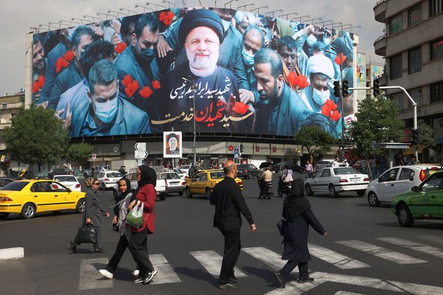People walk past a billboard with a picture of the late Iran's President Ebrahim Raisi on a street in Tehran, Iran on May 21, 2024. (Photo by Majid Asgaripour/WANA (West Asia News Agency) via Reuters)