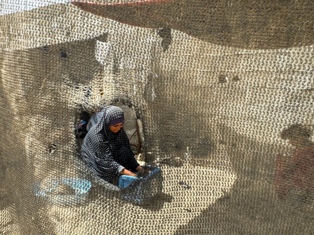 A displaced Palestinian woman, who fled her house due to Israel's military offensive, washes clothes at a tent camp, amid the ongoing conflict between Israel and Palestinian Islamist group Hamas, in Rafah, in the southern Gaza Strip on May 23, 2024. (Photo by Mohammed Salem/Reuters)