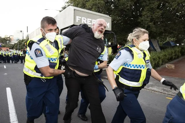 A man is arrested as police and protesters clash in Wellington, New Zealand, Tuesday, February 22, 2022, as police tightened a cordon around a protest convoy that has been camped outside Parliament for two weeks. The protesters, who oppose coronavirus vaccine mandates and were inspired by similar protests in Canada, appear fairly well organized after trucking in portable toilets, crates of donated food, and bales of straw to lay down when the grass turned to mud. (Photo by George Heard/New Zealand Herald via AP Photo)