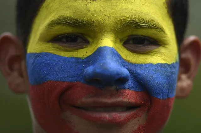 A government supporter, his face painted with the colors of the national flag, smiles during a march marking Youth Day, in Caracas, Venezuela, Saturday, February 12, 2022. (Photo by Matias Delacroix/AP Photo)