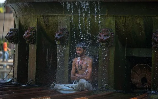 An indian man cools himself under a public fountain on a hot afternoon in New Delhi, India, Monday, May 2, 2016. Much of India is reeling under a weekslong heat wave and severe drought conditions that have decimated crops, killed livestock and left at least 330 million Indians without enough water for their daily needs. (Photo by Manish Swarup/AP Photo)