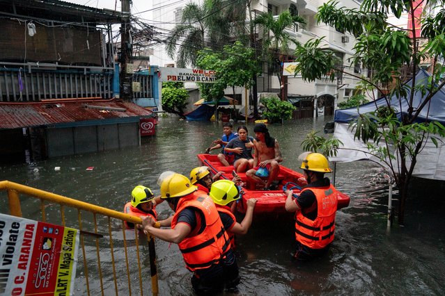 Rescuers assist residents along a flooded street amid heavy rains brought by Typhoon Gaemi, in Manila, Philippines, on July 24, 2024. (Photo by Lisa Marie David/Reuters)