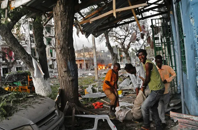 A victim is carried away from the scene of a terror attack at the Ambassador Hotel, after a car bomb exploded on June 1, 2016 at a top Mogadishu hotel that houses several MPs, killing several people, and followed by a gun battle. Somalia's Al-Qaeda-linked al-Shabaab group was chased out of the capital Mogadishu in 2011 but remains a dangerous threat in both Somalia and neighbouring Kenya, where it carries out frequent attacks. (Photo by Mohamed Abdiwahab/AFP Photo)