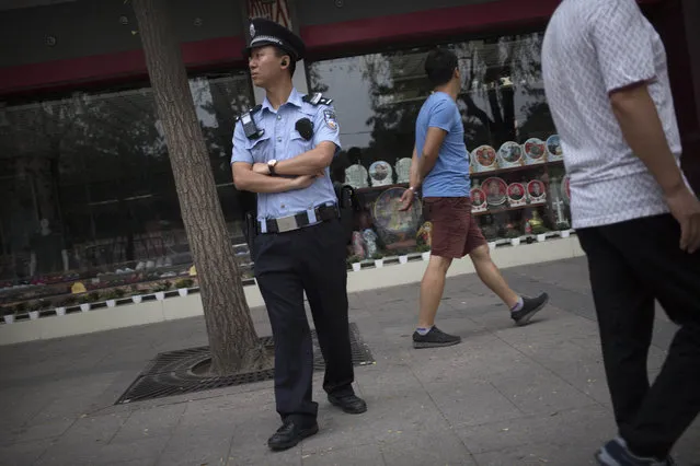 A police officer stands guard on the sidewalk of a street adjacent to Tiananmen Square in Beijing, Saturday, June 4, 2016. Saturday marks the 27th anniversary of China's bloody crackdown on pro-democracy protests centered on Beijing's Tiananmen Square. (Photo by Mark Schiefelbein/AP Photo)