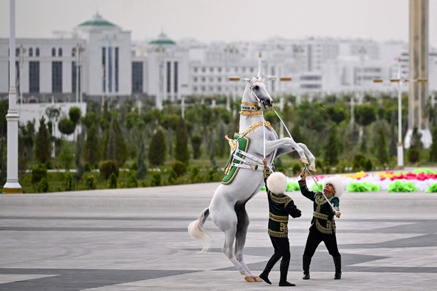 Jockeys perform with a horse during the ceremony inaugurating the new city of Arkadag - named in honour of Turkmenistan's former leader Gurbanguly Berdymukhamedov - in Arkadag, some 30 kilometres (18 miles) outside the capital Ashgabat, on June 29, 2023. The reclusive Central Asian country bordering the Caspian Sea has been ruled by the Berdymukhamedov family for more than 16 years. Gurbanguly Berdymukhamedov, a former dentist turned autocrat, officially stepped down as president of the ex-Soviet nation last year and was replaced by his son, Serdar Berdymukhamedov. But the 65-year-old, known for his personality cult, bears the title of “Arkadag” (Hero Protector) and continues to dominate the country. (Photo by Natalia Kolesnikova/AFP Photo)