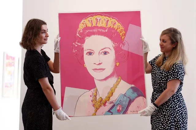 Gallery assistants pose with “Queen Elizabeth II of the United Kingdom, from Reigning Queens (F. & S. 336) 1985” by Andy Warhol, at a photocall before the artwork is due to be auctioned at Phillips in London, Britain, June 1, 2022. (Photo by Tom Nicholson/Reuters)