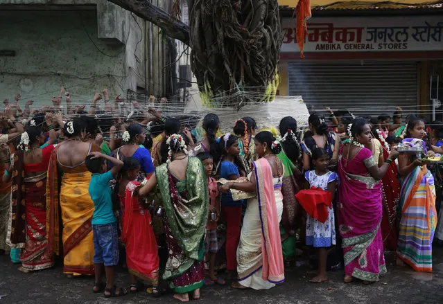 Indian Hindu married women tie cotton threads around a Banyan tree as they perform rituals on the occasion of Vat Savitri festival in Mumbai, India, Sunday, June 19, 2016. Vat Savitri is celebrated on a full moon day where women pray for the longevity of their husbands. (Photo by Rafiq Maqbool/AP Photo)