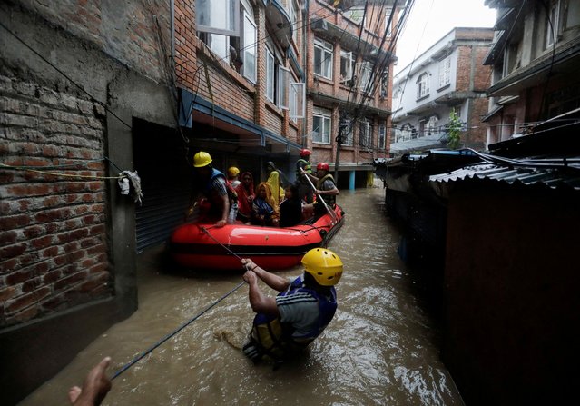 Security force members use an inflatable raft to bring residents to safety from a flooded area near the bank of the overflowing Bagmati River following heavy rains, in Kathmandu, Nepal on September 28, 2024. (Photo by Navesh Chitrakar/Reuters)