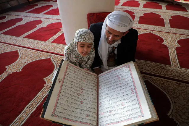A Muslim man listen as a child reads the Koran, Islam's holy book, at the Grand Mosque of Yemen's capital Sanaa on the first day of the holy month of Ramadan, on April 2, 2022. The Iran-backed Huthi rebels and Saudi-led coalition have both agreed to observe the two-month truce, which took effect at 1600 GMT on April 2, the first day of Ramadan, the Muslim holy fasting month. (Photo by Mohammed Huwais/AFP Photo)