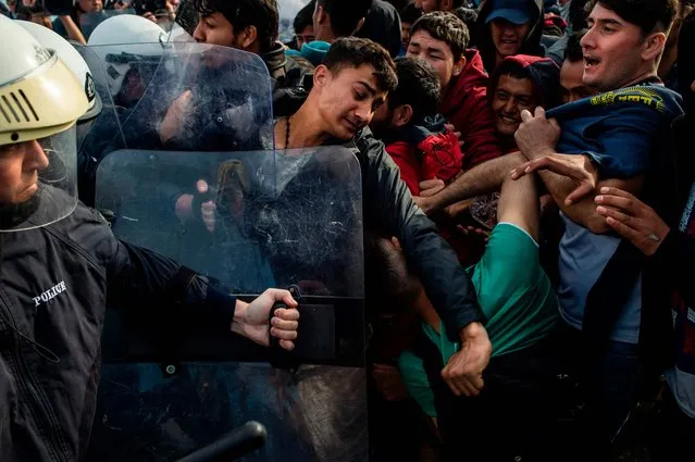 Migrants and refugees scuffle with riot police on the Greek Aegean island of Lesbos, on March 3, 2020, amid a migration surge from neighbouring Turkey after it opened its borders to thousands of refugees trying to reach Europe. Several aid groups on Greece's Lesbos said they were suspending work with refugees and evacuating staff on March 3 in the wake of violence and threats, as tensions soar on an island in the crosshairs of the migrant crisis. EU chiefs pledged millions of euros of financial assistance to Greece to help tackle the migration surge. (Photo by Angelos Tzortzinis/AFP Photo)