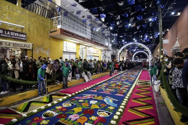 A group of artisans make colored sawdust rugs on the “Night Nobody Sleeps” of the municipality of Huamantla, Tlaxcala state, Mexico, early 15 August 2022. The sawdust rug of 3,932 meters broke the Guinness record for the world's longest rug of this type, where 240 artisans participated with 80 tons of multi-colored sawdust. (Photo by Hilda Rios/EPA/EFE)