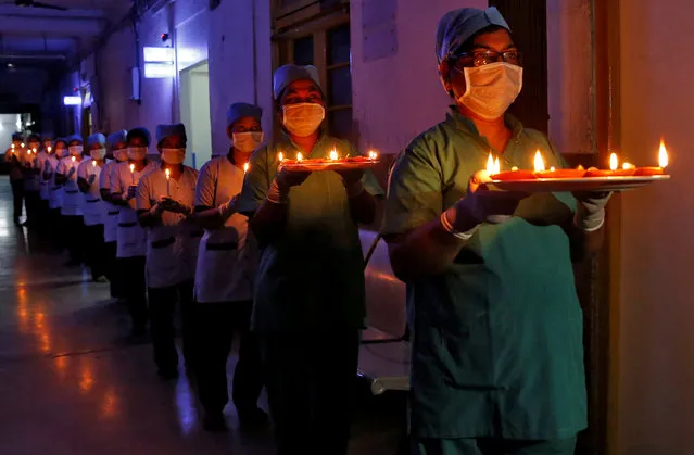 Staff members of a hospital carry candles and oil lamps to show solidarity with people who are affected by the coronavirus disease (COVID-19), and with doctors, nurses and other healthcare workers from all over the world during a 21-day nationwide lockdown to slow the spreading of the disease, in Kolkata, India, April 5, 2020. (Photo by Rupak De Chowdhuri/Reuters)