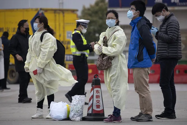 Residents wearing protective gear wait near a toll booth where some are entering the city of Wuhan which is still under lockdown due to the coronavirus outbreak but have started allowing some residents to return in central China's Hubei province on Thursday, April 2, 2020. (Photo by Ng Han Guan/AP Photo)