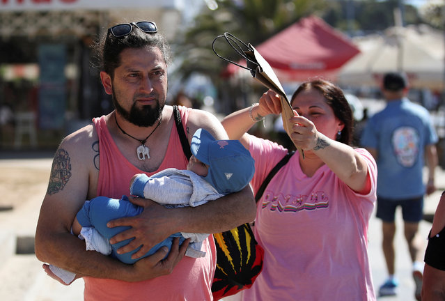 A woman covers her son from the sun with a cardboard bag during a heatwave hitting the country, in Vina del Mar, Chile, on December 19, 2024. (Photo by Rodrigo Garrido/Reuters)