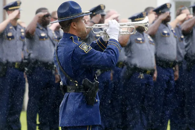 A Louisiana State Trooper plays “Taps” on a trumpet during funeral services for Baton Rouge Police Department officer Montrell Jackson at Greenoaks Memorial Park in Baton Rouge, Louisiana, U.S. July 25, 2016. (Photo by Jonathan Bachman/Reuters)