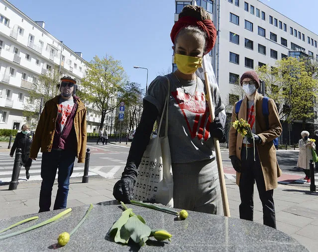 People place down daffodils in Warsaw, Poland, Sunday, April 19, 2020 in memory with the fighters  during anniversary ceremony for the ill-fated struggle of the 1943 Warsaw Ghetto Uprising. Observances were scaled down and no crowd was in attendance due to the new coronavirus spread and requirements of social distancing. (Photo by Czarek Sokolowski/AP Photo)