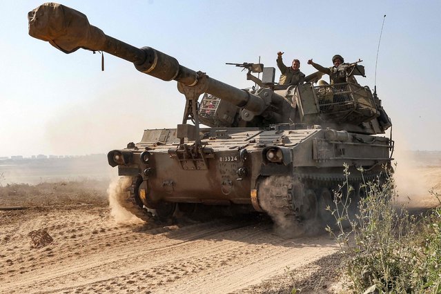 An Israeli army soldier gestures while seated in the hatch of an artillery howitzer moving near the border with the Gaza Strip in southern Israel on November 3, 2023 amid the ongoing battles between Israel and the Palestinian group Hamas in the Gaza Strip. (Photo by Jack Guez/AFP Photo)