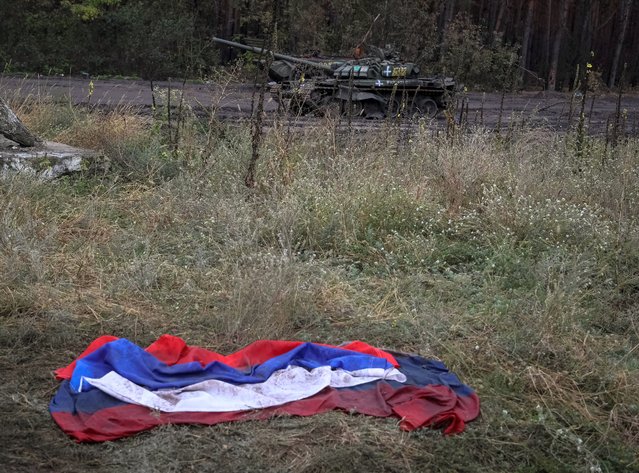 A Russian national flag lies on the ground near a destroyed Russian tank, as Russia's attack on Ukraine continues, in the town of Izium, recently liberated by Ukrainian Armed Forces, in Kharkiv region, Ukraine on September 14, 2022. (Photo by Gleb Garanich/Reuters)