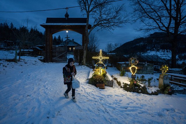A boy walks at the cemetery after church Christmas service in Kryvorivnia village, Ukraine, Sunday, December 24, 2023. (Photo by Evgeniy Maloletka/AP Photo)