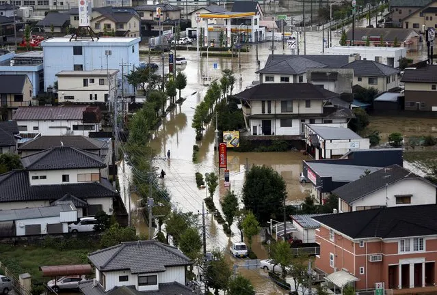 Local residents wade through a residential area flooded by the Kinugawa river, caused by typhoon Etau, in Joso, Ibaraki prefecture, Japan, September 11, 2015. (Photo by Issei Kato/Reuters)