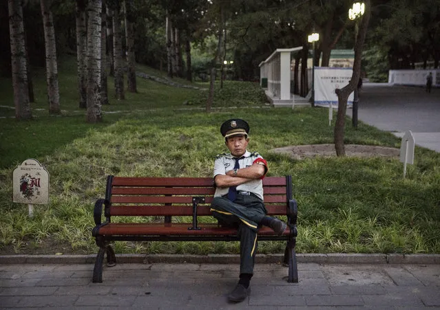 A Chinese security guard sits on a bench as he watches over a park on September 17, 2014 in Beijing, China. (Photo by Kevin Frayer/Getty Images)
