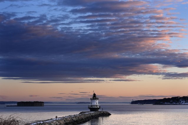 A women watches her step as she walks along an icy breakwall after watching the sunrise at Spring Point Light, Wednesday, February 26, 2025, in South Portland, Maine. (Photo by Robert F. Bukaty/AP Photo)