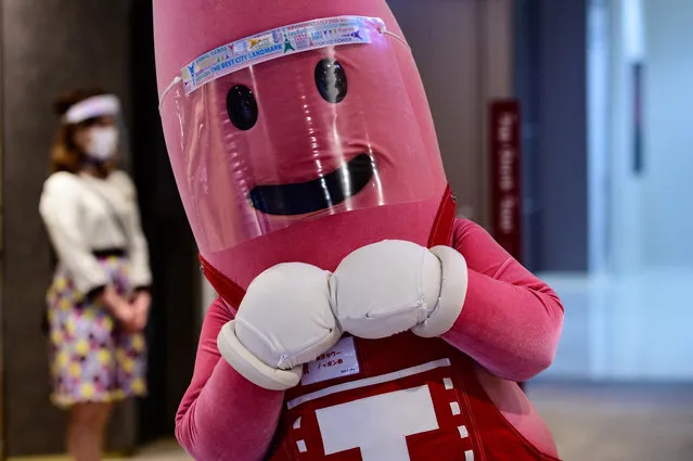 A person dressed as the mascot of Tokyo Tower wears a face shield while waiting to greet patrons at the entrance of the 332.9m (1,092ft.) high tower on May 28, 2020, as the city's landmark reopened following the lifting on May 25 of the state of emergency, imposed due to the COVID-19 novel coronavirus outbreak. (Photo by Philip Fong/AFP Photo)