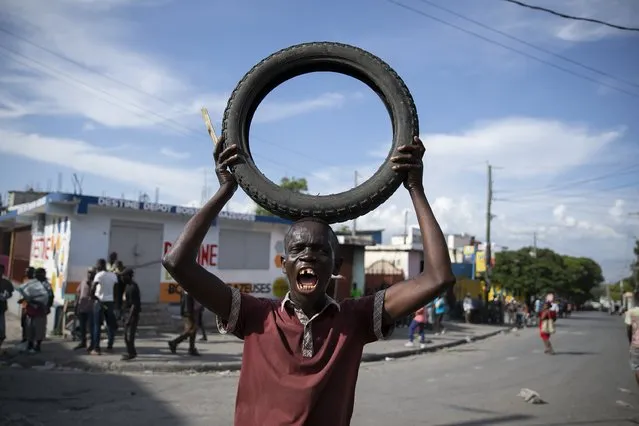 A protester shouts anti-American slogans while holding a tire to be added to a burning barricade during a protest against the government's request for an international military force, in Port-au-Prince, Haiti, Friday, October 21, 2022. (Photo by Joseph Odelyn/AP Photo)
