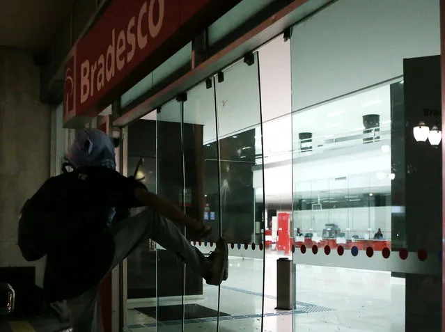A person kicks the glass door of a bank in downtown Sao Paulo, Brazil August 31, 2016. (Photo by Paulo Whitaker/Reuters)