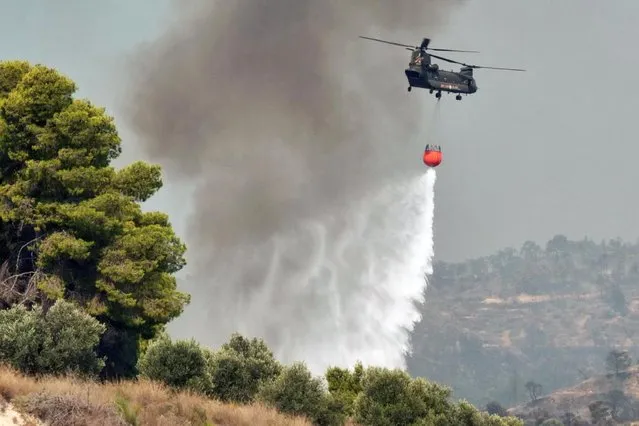 A Chinook helicopter makes a water drop as a wildfire burns near the village of Galataki, Greece, July 23, 2020. (Photo by Vassilis Triandafyllou/Reuters)