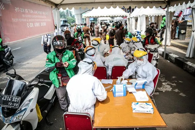 Healthcare workers wearing protective gear collect samples through a plexiglass wall during a COVID-19 rapid test in Jakarta, Indonesia, on August 6, 2020. Indonesia has so far recorded the highest number of COVID-19 cases in South East Asia. (Photo by Jefta Images/Barcroft Media via Getty Images)
