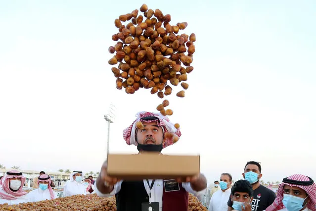 A Saudi farmer throws dates in the air during Unaizah Season for Dates, at Unaizah city in Al-Qassim province, Saudi Arabia on August 15, 2020. (Photo by Ahmed Yosri/Reuters)