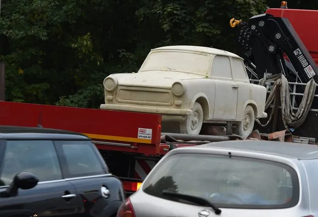 A Trabant 601 statue carved from a 25-ton block of sandstone by sculptor Carlo Wloch is transported on a truck after being loaded onto the vehicle at a workshop in Berlin, Germany, 06 October 2015. The artwork that weighs nine tons will be showcased at the vintage car fair Motorworld Classics in Berlin, which will run from 08 to 11 October 2015. (Photo by Jens Kalaene/EPA)